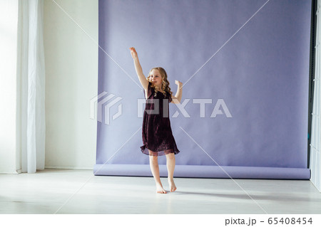 Beautiful little girl in dress dances alone at home 65408454