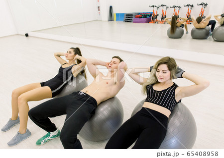 fitness, sport, training and people concept - smiling girls and boy flexing abdominal muscles with exercise ball in gym fitness, sport, training and people concept - smiling girls and boy flexing abdominal muscles with exercise ball in gym 65408958