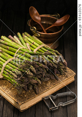 Bunch of fresh green asparagus spears on a rustic wooden table 65410376