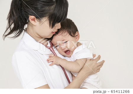 泣く赤ちゃんを抱き世話をする白衣の看護師 65411266