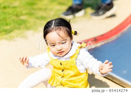 幼児 公園 家族 すべり台で遊ぶかわいい女の子の写真素材