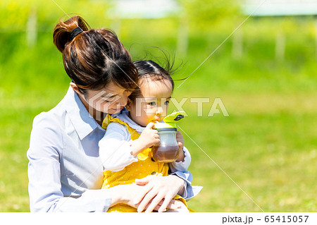 幼児　公園　家族　ママに抱かれてお茶を飲む女の子 65415057