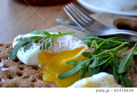 Poached egg on a whole grain bread with arugula Poached egg on a whole grain bread with arugula 65416639
