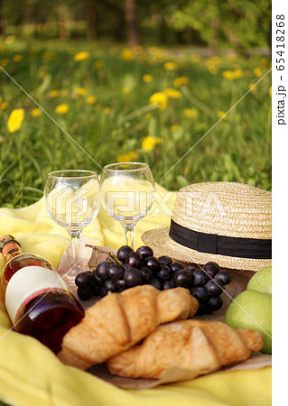 Picnic on the grass with croissant, pink wine, straw hat, grape on yellow plaid Picnic on the grass with croissant, pink wine, straw hat, grape on yellow plaid 65418268