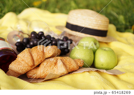 Picnic on the grass with croissant, pink wine, straw hat, grape on yellow plaid Picnic on the grass with croissant, pink wine, straw hat, grape on yellow plaid 65418269