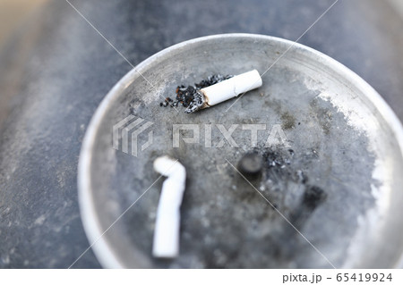 Two white cigarette butts lying in ash tray Two white cigarette butts lying in ash tray 65419924