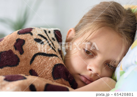 Girl slowly wakes up, lying in bed and covered 65420801