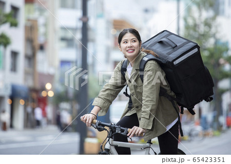 自転車で荷物の配送を行う若い女性 65423351