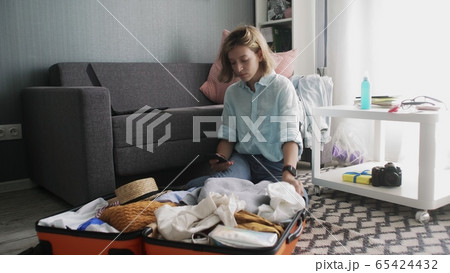 Cute girl with a phone in her hands checks the list of things to travel 65424432