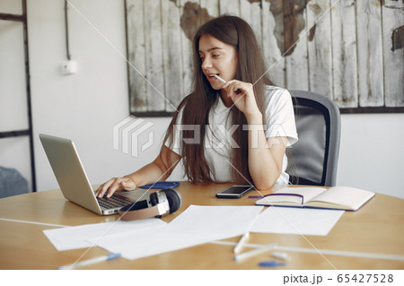 Young student sitting at the table and use the laptop Young student sitting at the table and use the laptop 65427528