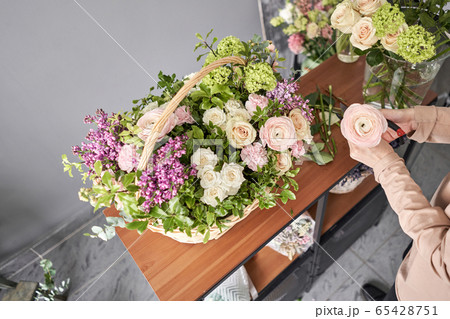 Education in the school of floristry. Master class on making bouquets. Summer bouquet in a wicker basket.. Learning flower arranging, making beautiful bouquets with your own hands. Flowers delivery 65428751