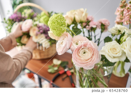 Education in the school of floristry. Master class on making bouquets. Summer bouquet in a wicker basket.. Learning flower arranging, making beautiful bouquets with your own hands. Flowers delivery 65428760