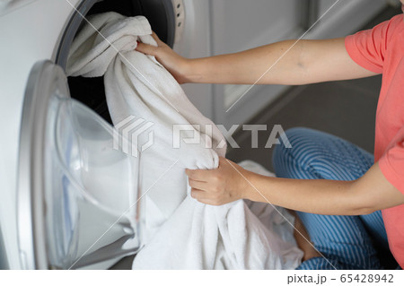 A girl loads dirty laundry into a washing machine A girl loads dirty laundry into a washing machine 65428942