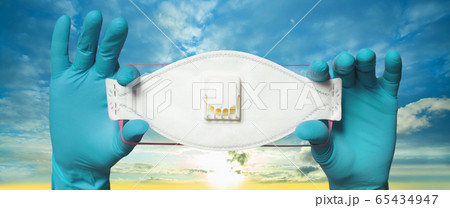 Hands wearing doctor gloves holding protective mask 65434947
