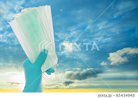 Doctor hand with protective mask on sky clouds 65434948