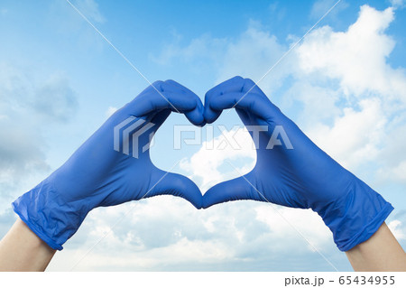 Doctor hands showing heart against sky clouds 65434955