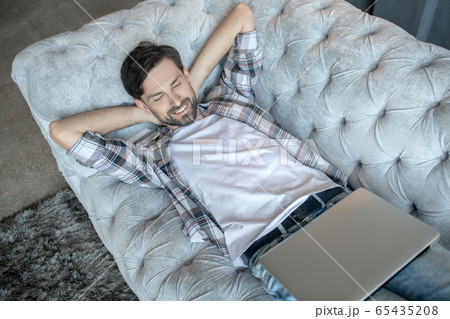 Young bearded man lying on sofa with his eyes closed. 65435208