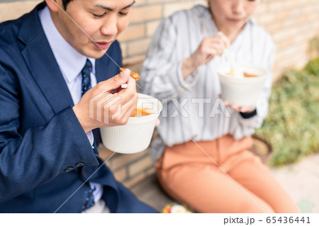 テイクアウトのカレーを食べる男女のアジア人会社員 65436441