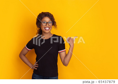 African-american beautiful young woman's portrait on yellow studio background, emotional and expressive. Copyspace for ad. African-american beautiful young woman's portrait on yellow studio background, emotional and expressive. Copyspace for ad. 65437879