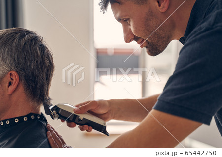 Young Caucasian man cutting hair of grey-haired person 65442750