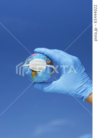 man wearing gloves showing a globe with a mask 65444022