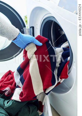 man putting clothes into the washing machine man putting clothes into the washing machine 65444024
