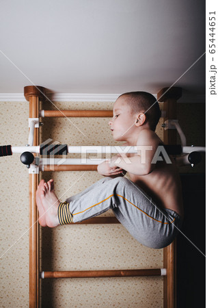 Home workout. The boy raises his legs in the hang 65444651