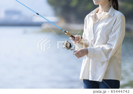 海辺で釣りを楽しむ若い女性の写真素材
