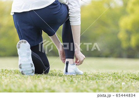 靴紐を結び運動の準備をする若い女性 65444834