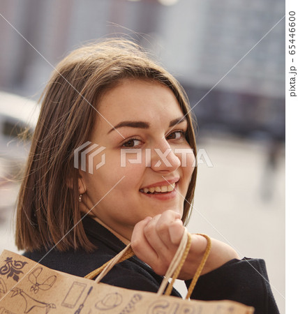Smiling girl with shopping bags in a city 65446600