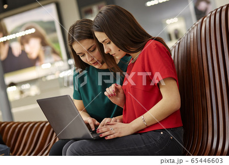 Two women students studying in open space with laptop computer. 65446603