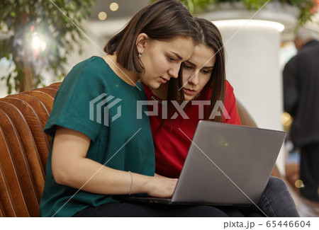 Two women students studying in open space with laptop computer. 65446604
