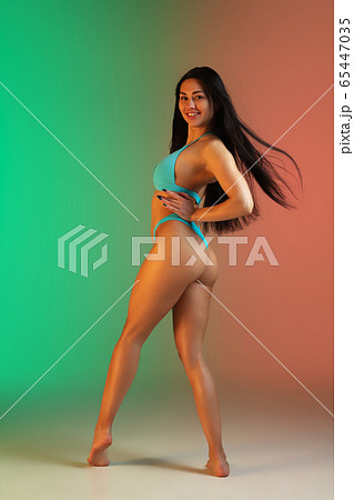 Fashion portrait of young fit and sportive woman in stylish blue luxury swimwear on gradient background. Perfect body ready for summertime. Fashion portrait of young fit and sportive woman in stylish blue luxury swimwear on gradient background. Perfect body ready for summertime. 65447035