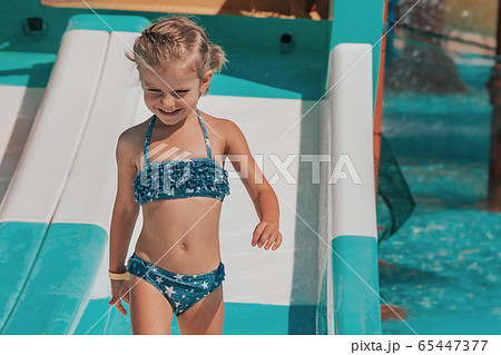 happy little girl splashing around in the pool 65447377