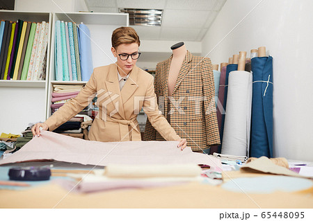 Tailor working with fabric in workshop 65448095