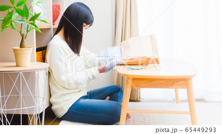 郵便物を開封する女性　洋服　コピースペース　16:9 65449293