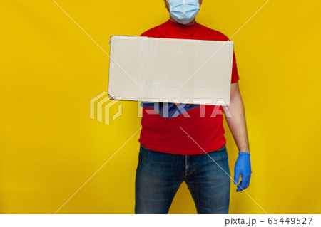 Delivery man in medical mask holding a cardbox on 65449527