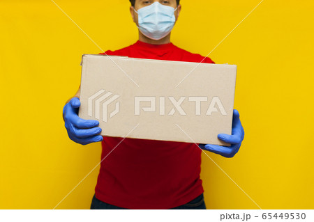 Delivery man in medical mask holding a cardbox on 65449530