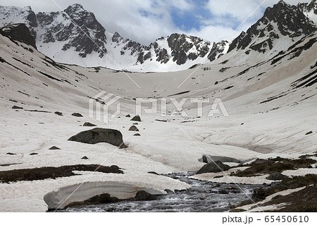 River with snow bridges in high snowy mountains at 65450610