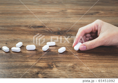 Hand with white tablets on wooden table. Medicine Hand with white tablets on wooden table. Medicine 65451092