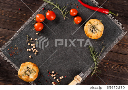 Wheat cakes, fresh tomatoes, rosemary and chickpeas, on a dark background. 65452830