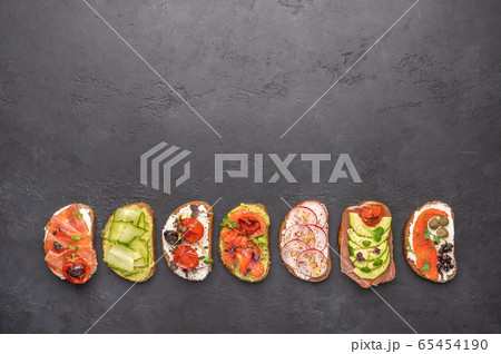 Homemade sandwiches with bread and various ingredients and spices on a dark background. Healthy Homemade sandwiches with bread and various ingredients and spices on a dark background. Healthy 65454190