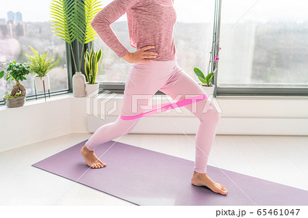 Resistance band fitness home workout woman doing lunges using loop bands for legs exercise step front and side to side exercises with strap elastic. Glute muscle activation for thighs cellulite 65461047