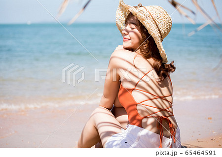 浜辺に座る水着姿の女性 65464591
