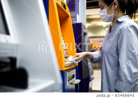 Asian woman at the cash machine withdraw money,girl is using tissue paper to press the ATM keyboard instead of the finger,avoid infection,during the Coronavirus outbreak,contagious disease of Covid-19 65466643