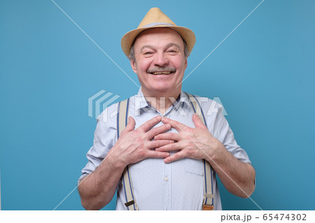 Cheerful senior man smiles happily, keeps hands on 65474302