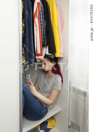 Young girl sad sits in wardrobe and looks into 65476260