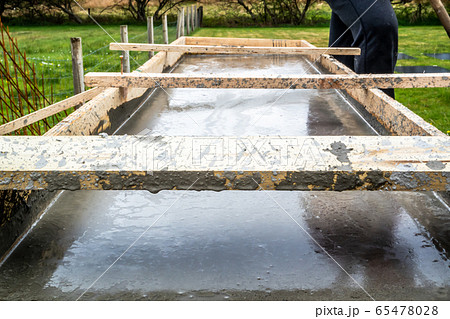 Steel rod reinforcement during pouring concrete into wooden frame Steel rod reinforcement during pouring concrete into wooden frame 65478028