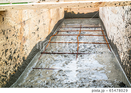 Steel rod reinforcement during pouring concrete into wooden frame 65478029