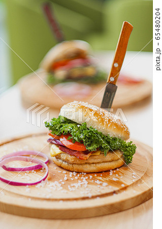 Delicious juicy hamburger on a served wooden board on a lighten bright background. Cutlets, buns, and vegetables. 65480204